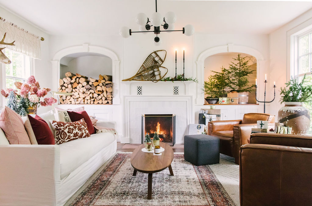 AS5A2087 Winter cottage cabin with a loloi rug, white, pink, and burgundy accents, and cozy fireplace.