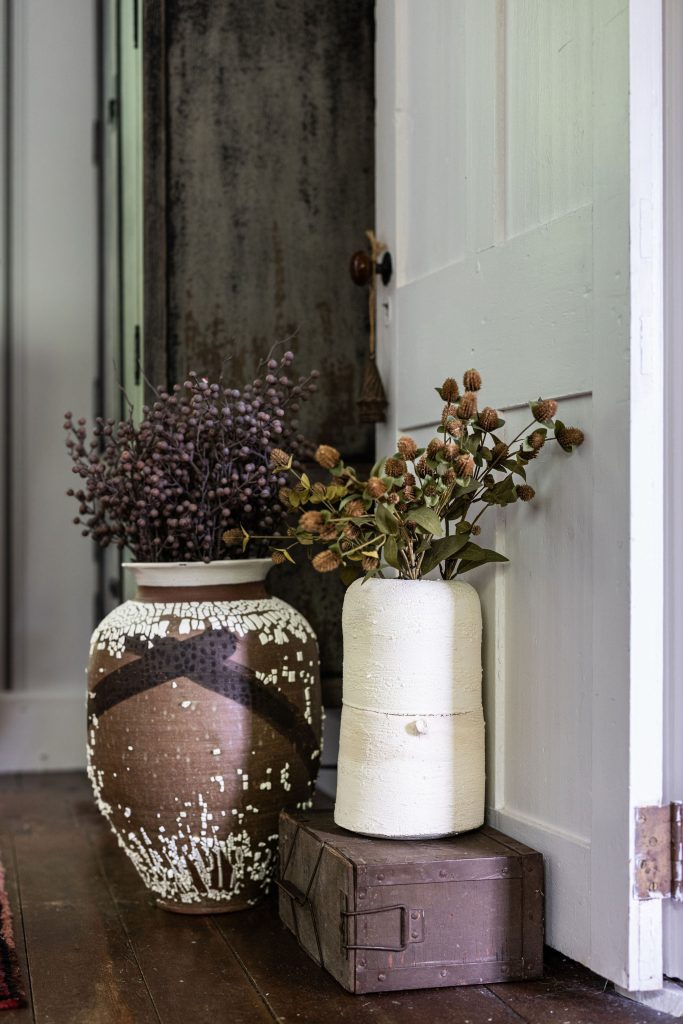 Faux plants in rustic clay pots in a entryway