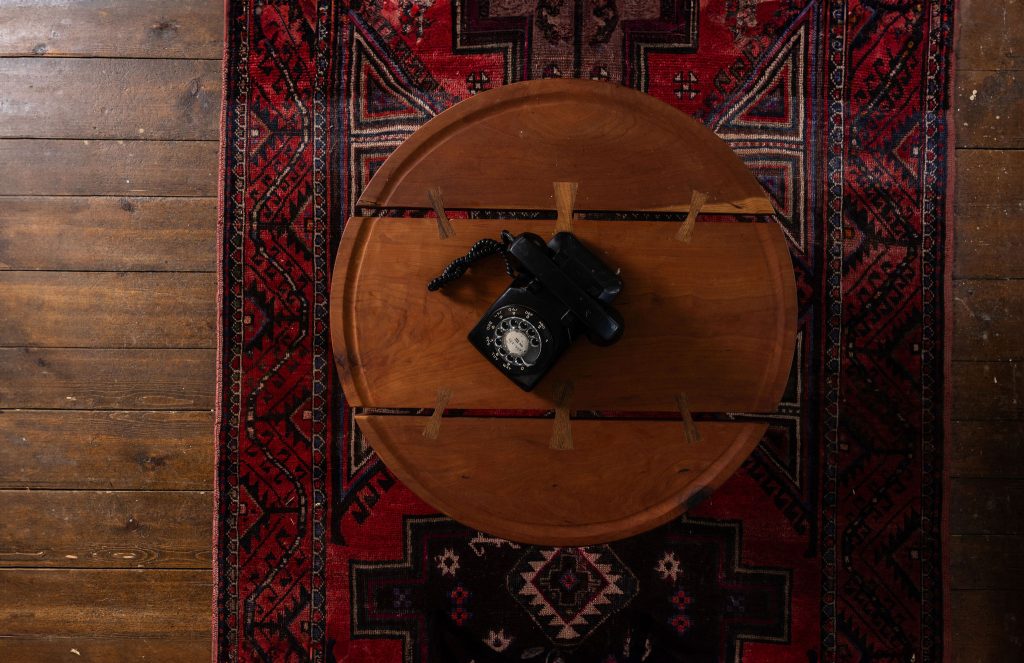 Birds eye view of round wood table with payphone on a carpet
