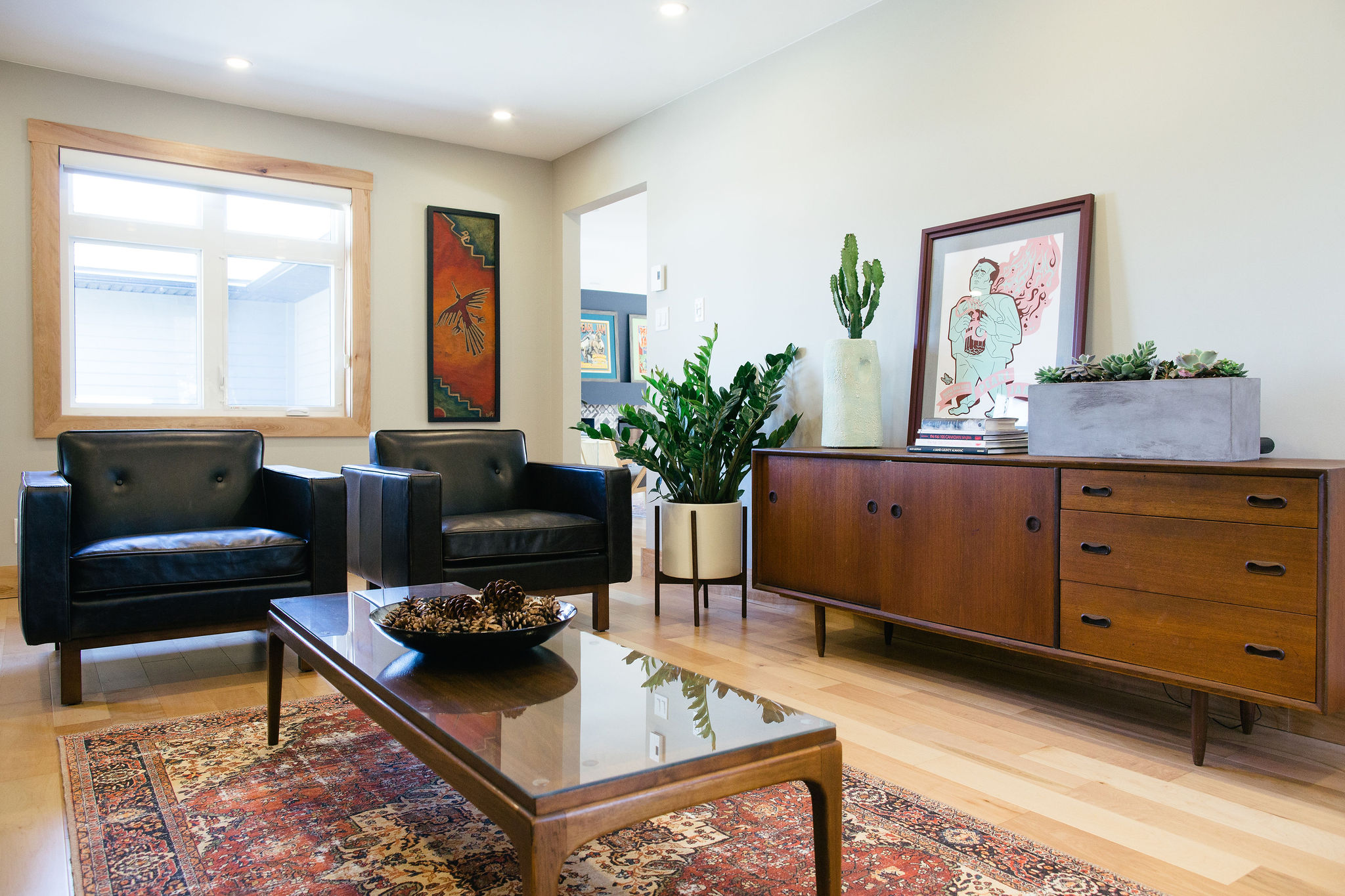 Shawn Hingley Red loloi vintage inspired rug in a living room with black armchairs and dark wood credenza