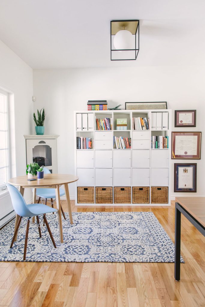 Study room with light white and blue accents and a large modular book shelf.