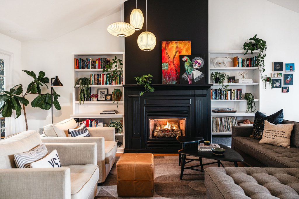 Inviting living room with black fireplace, neutral furniture, open bookshelves, and plants
