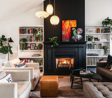 Inviting living room with black fireplace, neutral furniture, open bookshelves, and plants