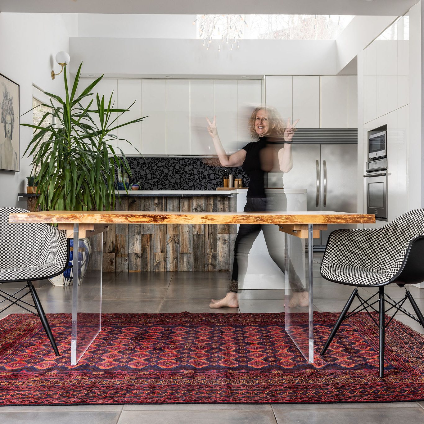 TUCKRUGS-17 Vintage rug in a modern, open concept dining room with wood slab table and person walking by